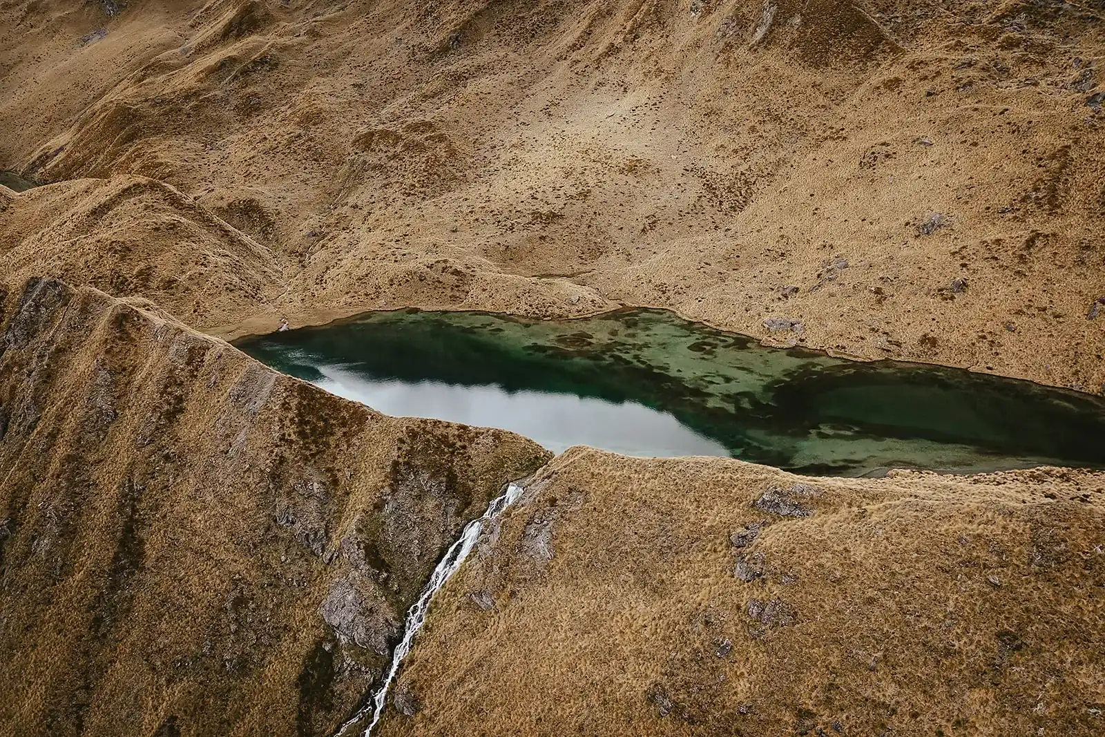 Aerial view of an emerald alpine tarn used as a helicopter landing site