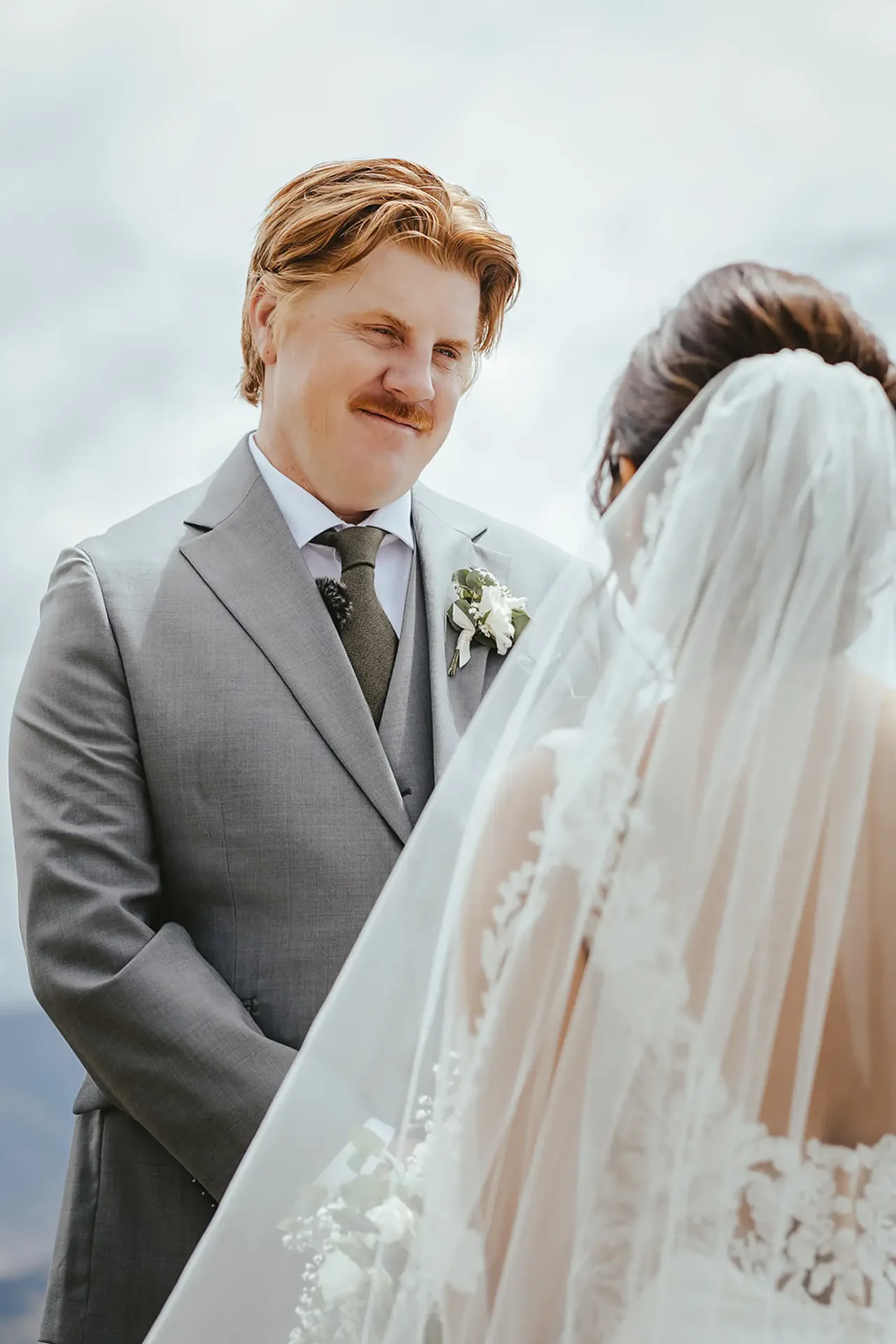 Groom smiling at the bride in her veil during the ceremony