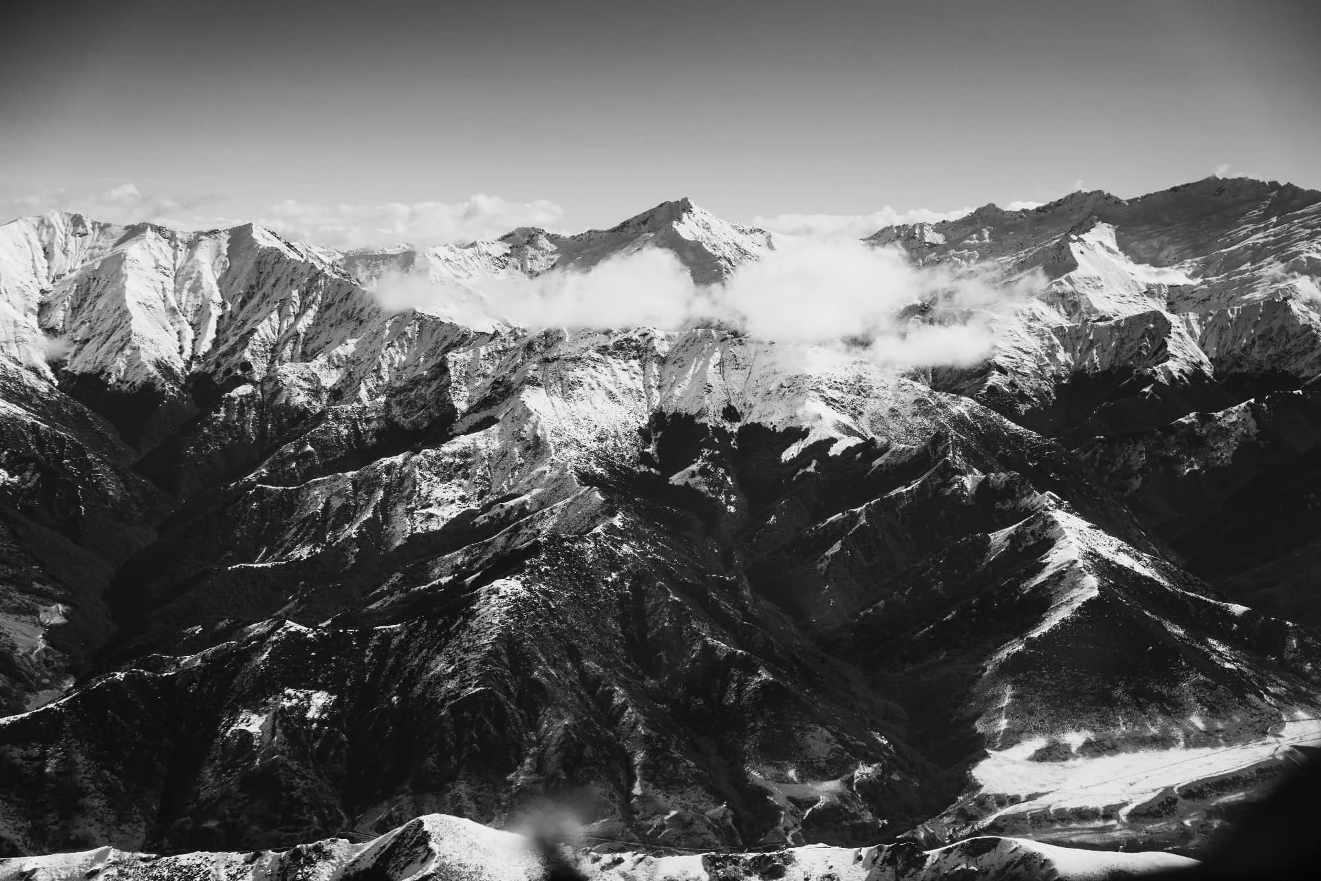 Black and white aerial view of snow-covered Southern Alps ridgelines above Wānaka