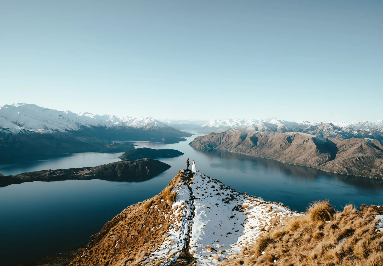 Aerial view along the tussock ridge at Coromandel Peak with the islands of Lake Wānaka below