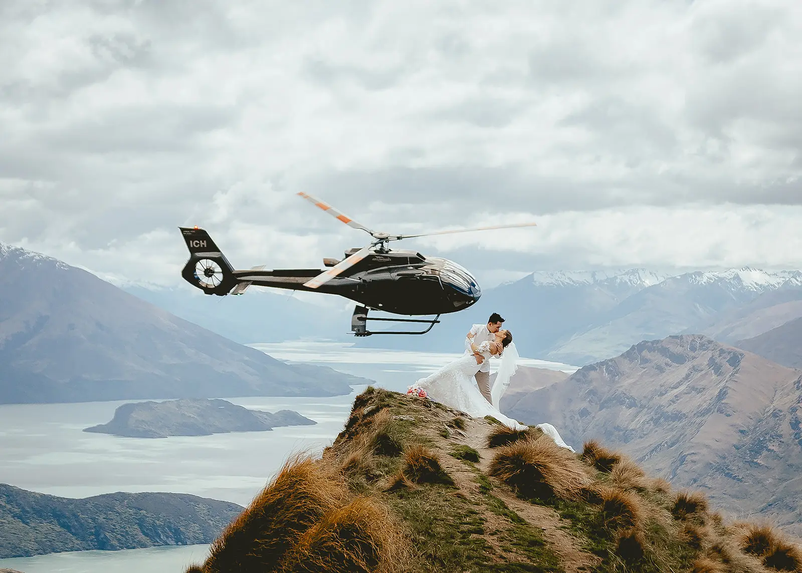 Couple in a dip kiss at Coromandel Peak with Lake Wānaka behind