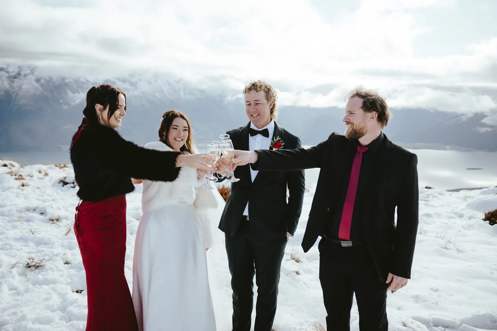 Two witnesses toasting with a bride and groom on a snow-covered alpine landing