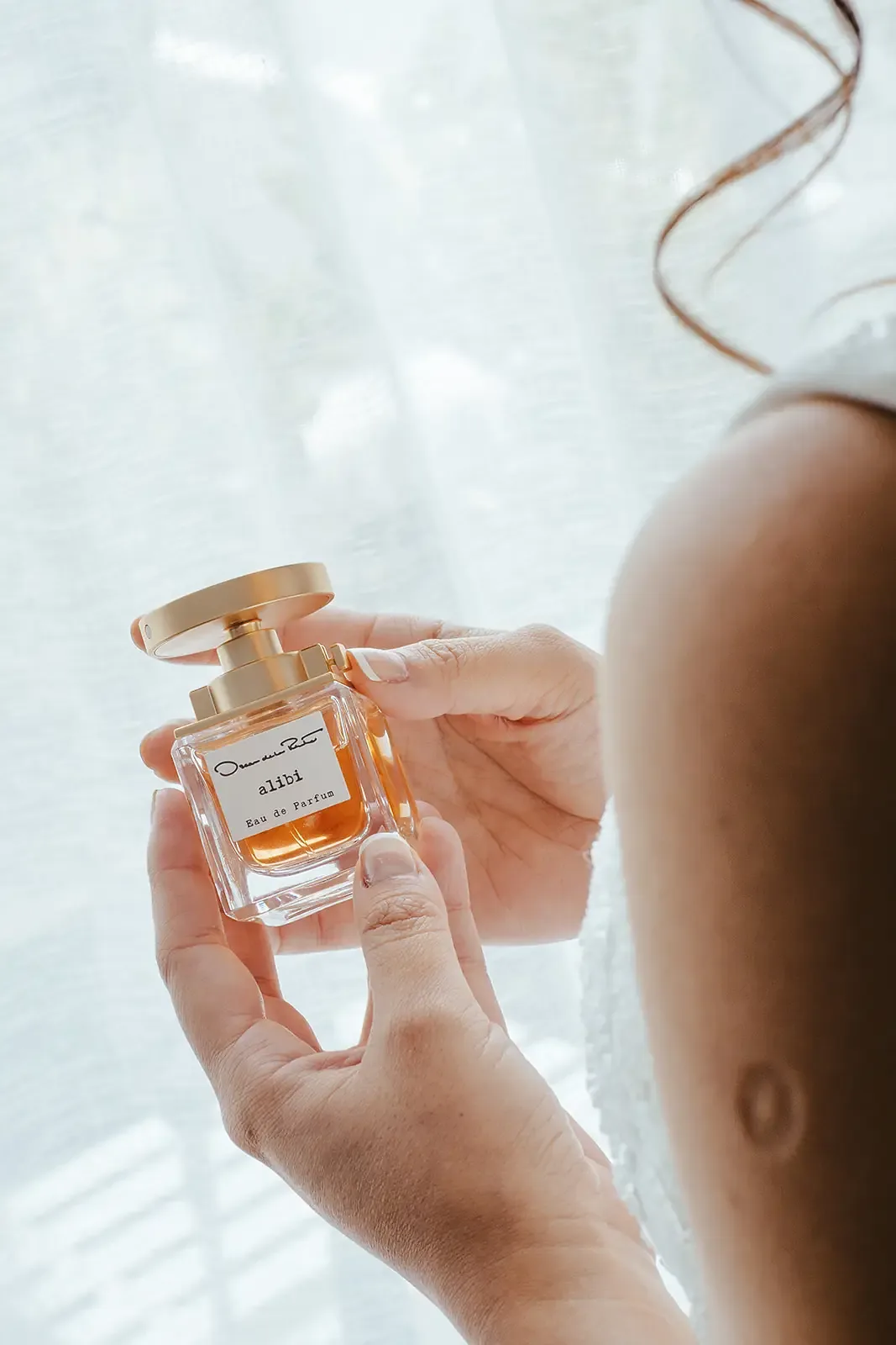 Bride holding a perfume bottle while getting ready
