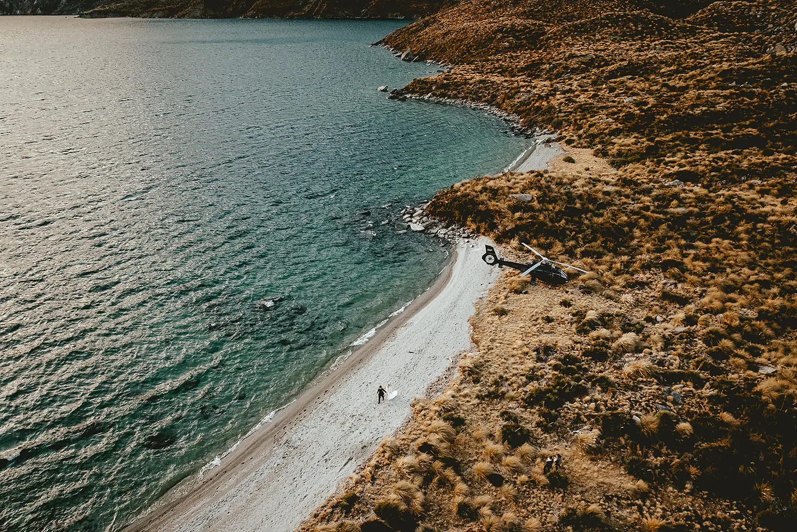 Aerial view of a couple and the helicopter on the alpine beach at Lochnagar