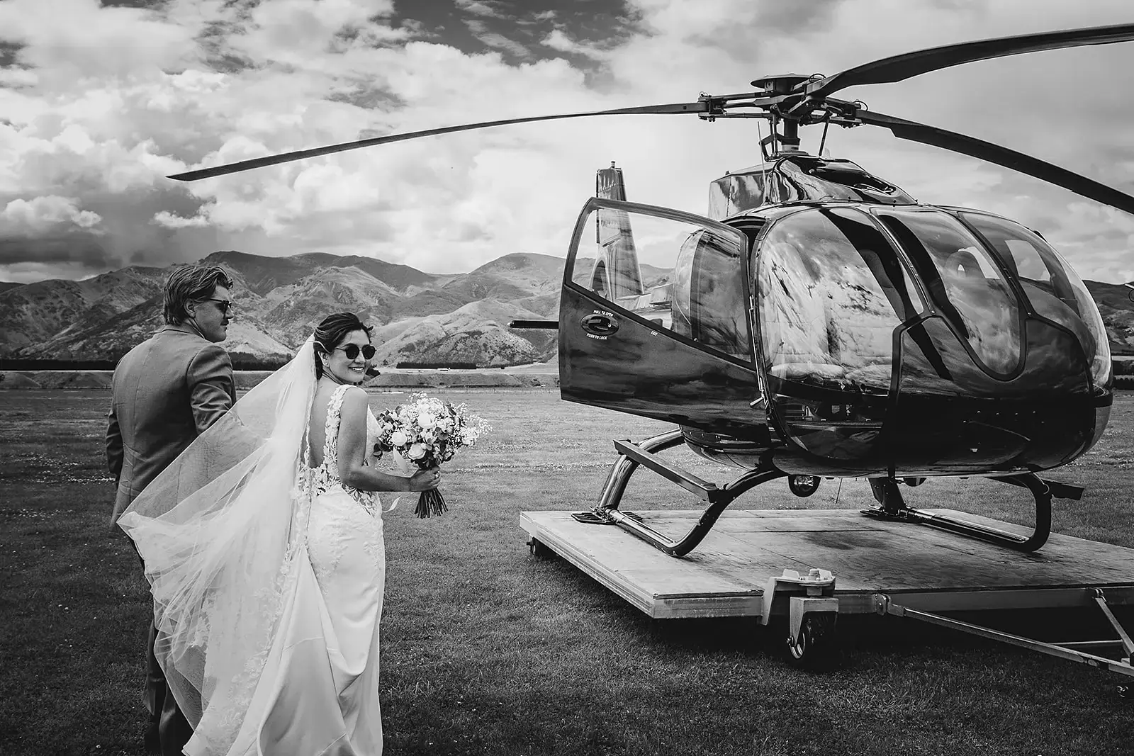 Bride and groom at the airfield beside a helicopter, black and white