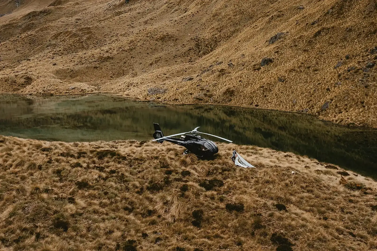 Couple beside a parked helicopter, veil lifting, seen from above