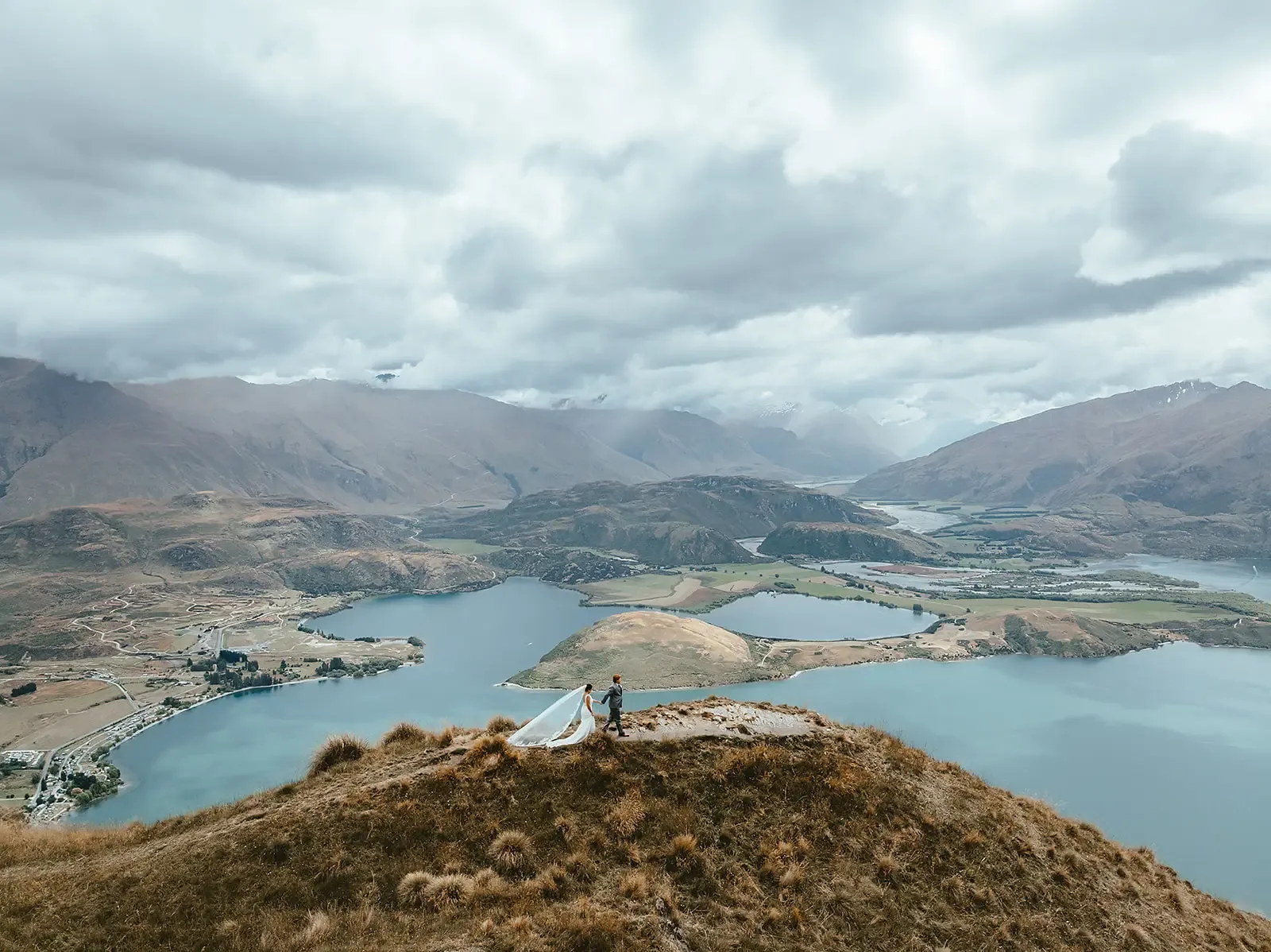 Couple walking along the summit with a Lake Wānaka panorama