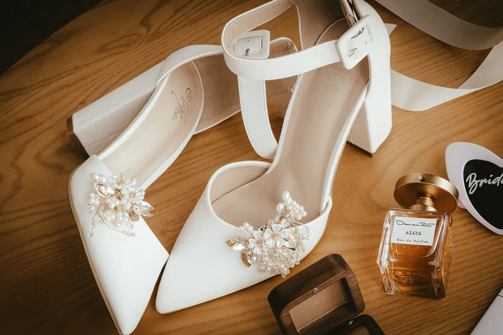 Bridal shoes with pearl detail beside perfume before the ceremony