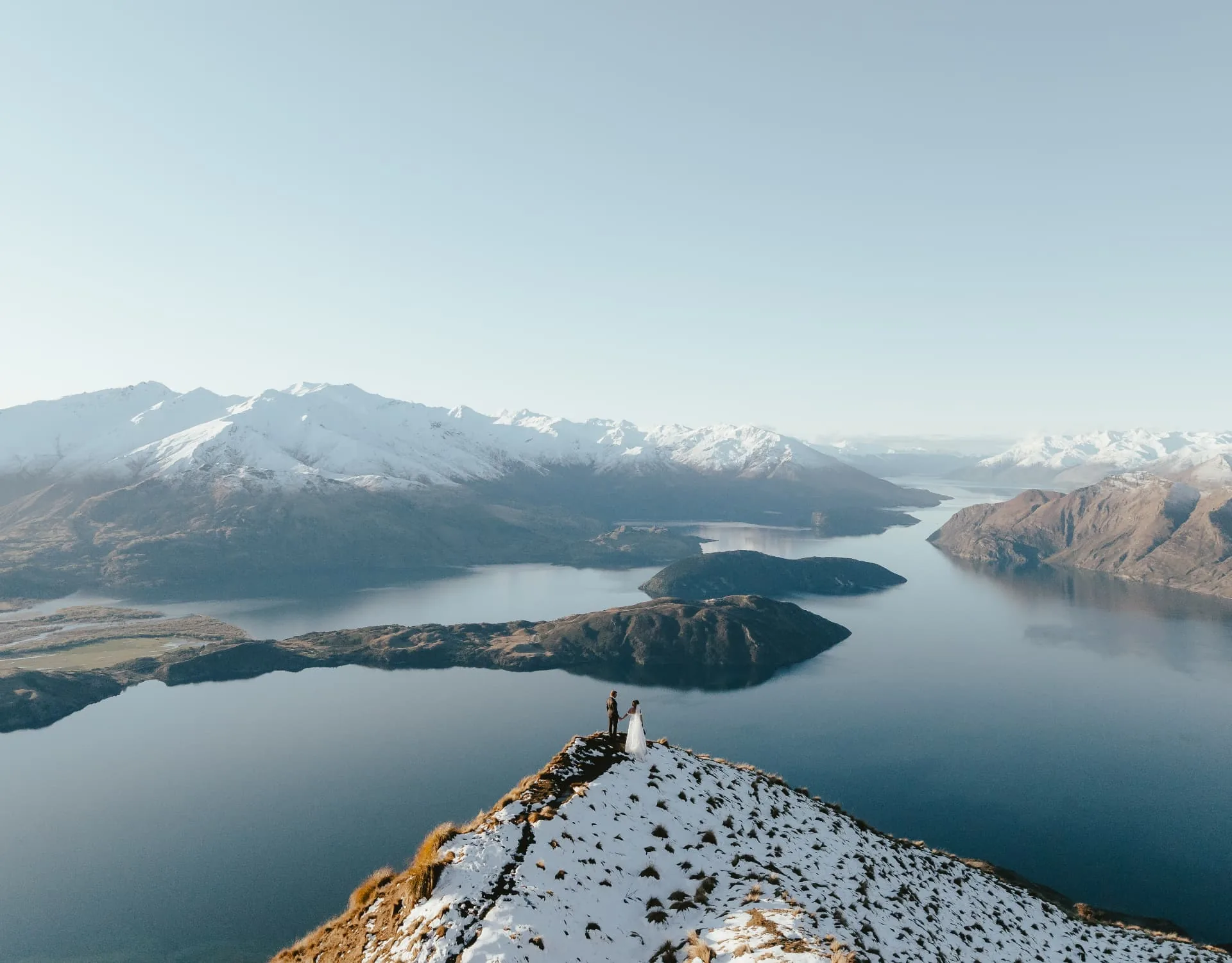 Bride and groom on the snow-dusted summit of Coromandel Peak above Lake Wānaka