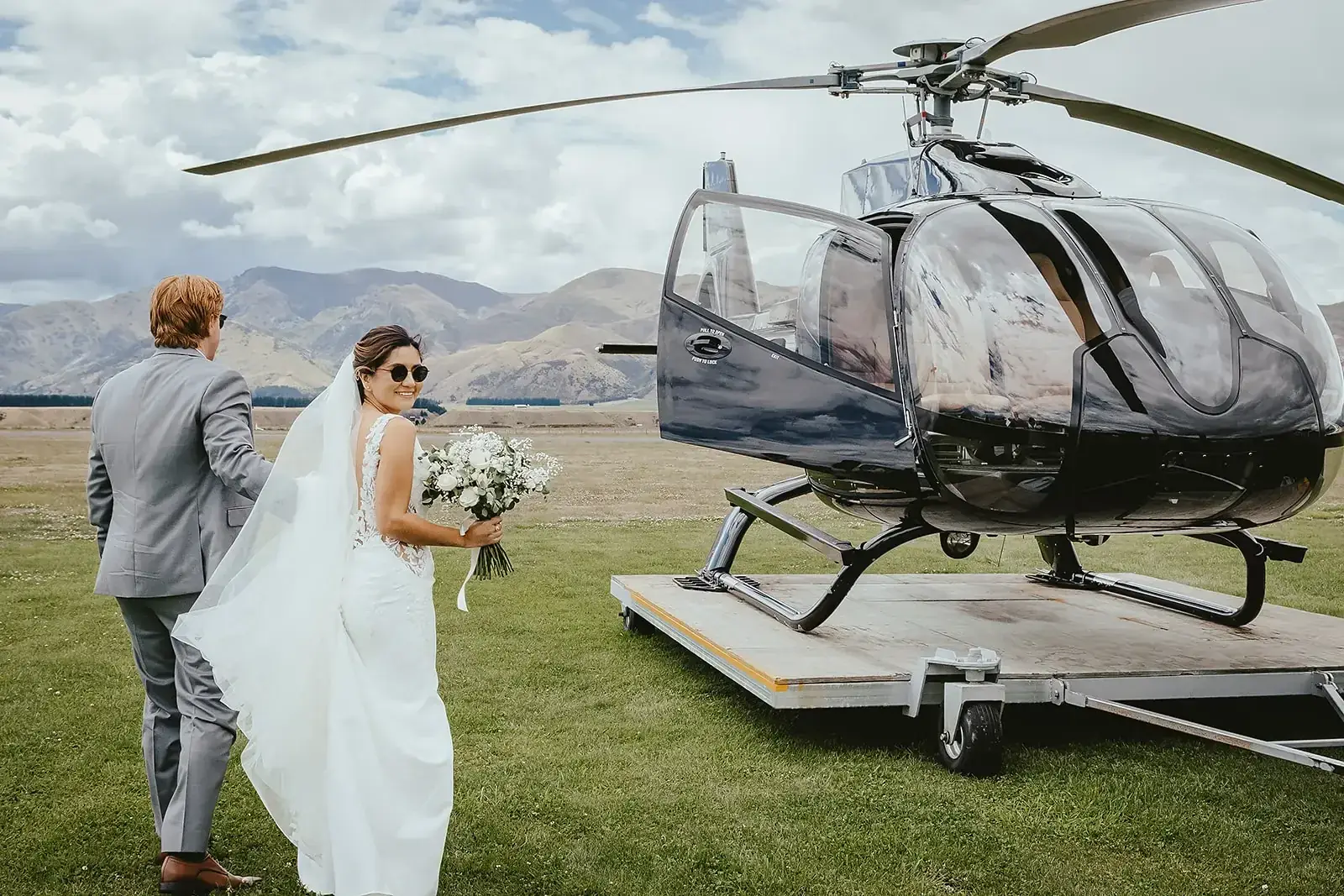 Bride and groom walking to a helicopter at the airfield