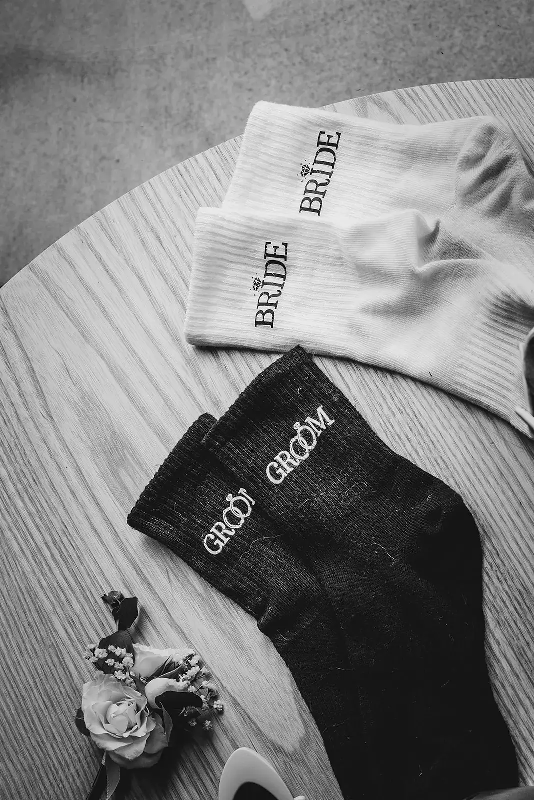 Flatlay of the groom's socks and buttonhole, black and white