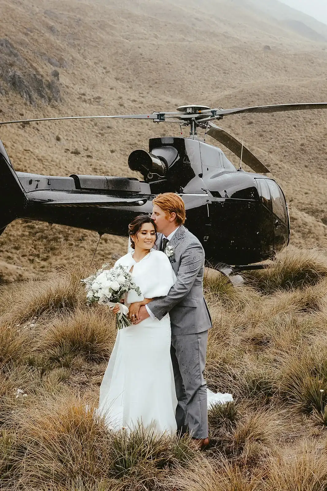 Couple embracing beside a helicopter in rain